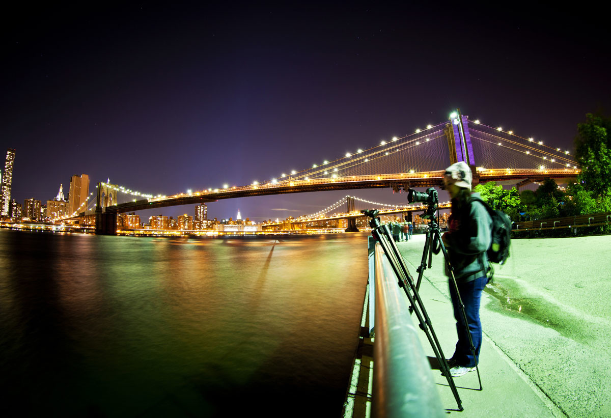 Female photographer taking a picture in front of Brooklyn Bridge