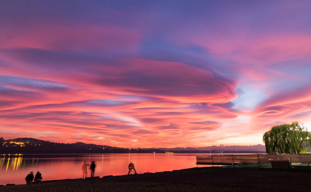 Tramonto sul lago tra nubi colorate e riflessi sull’acqua